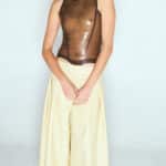 Model wearing a transparent smoky brown latex top and yellow culotte skirt by Sarah Chalal, handmade in Paris.